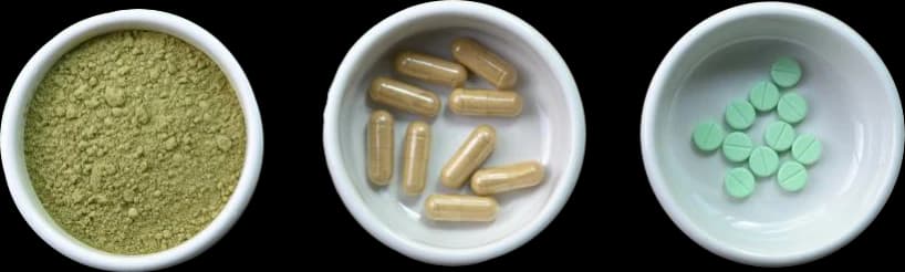 Kratom in white bowls in various forms: powder, pills, and tablets