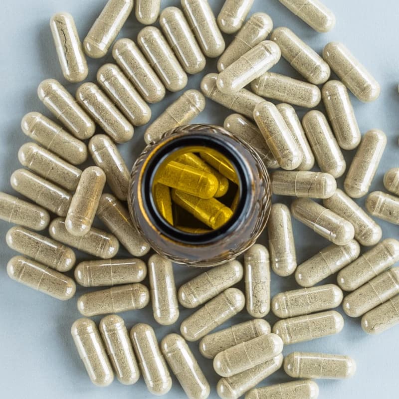 Pills bottle surrounded with capsules of kratom